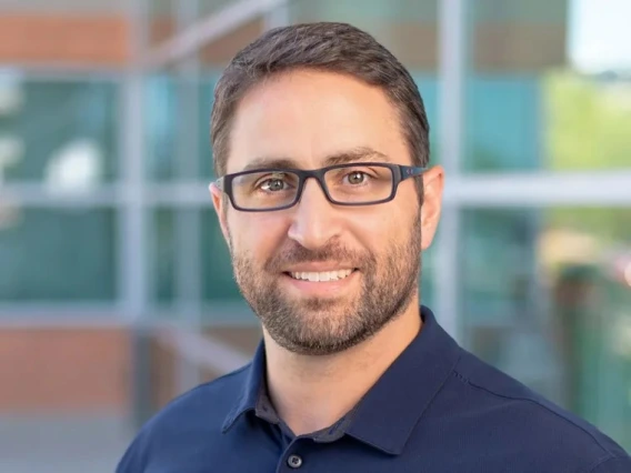 A photo of a man wearing black glasses and a blue shirt 