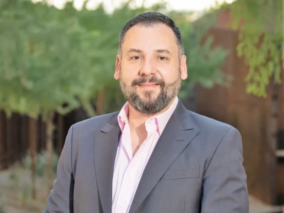 A photo of a man in a light pink shirt and a grey blazer
