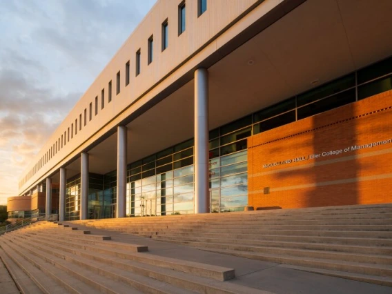 A photo of Eller College of Management with the sunset behind it