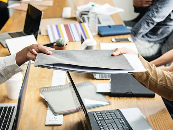 people holding file at desk