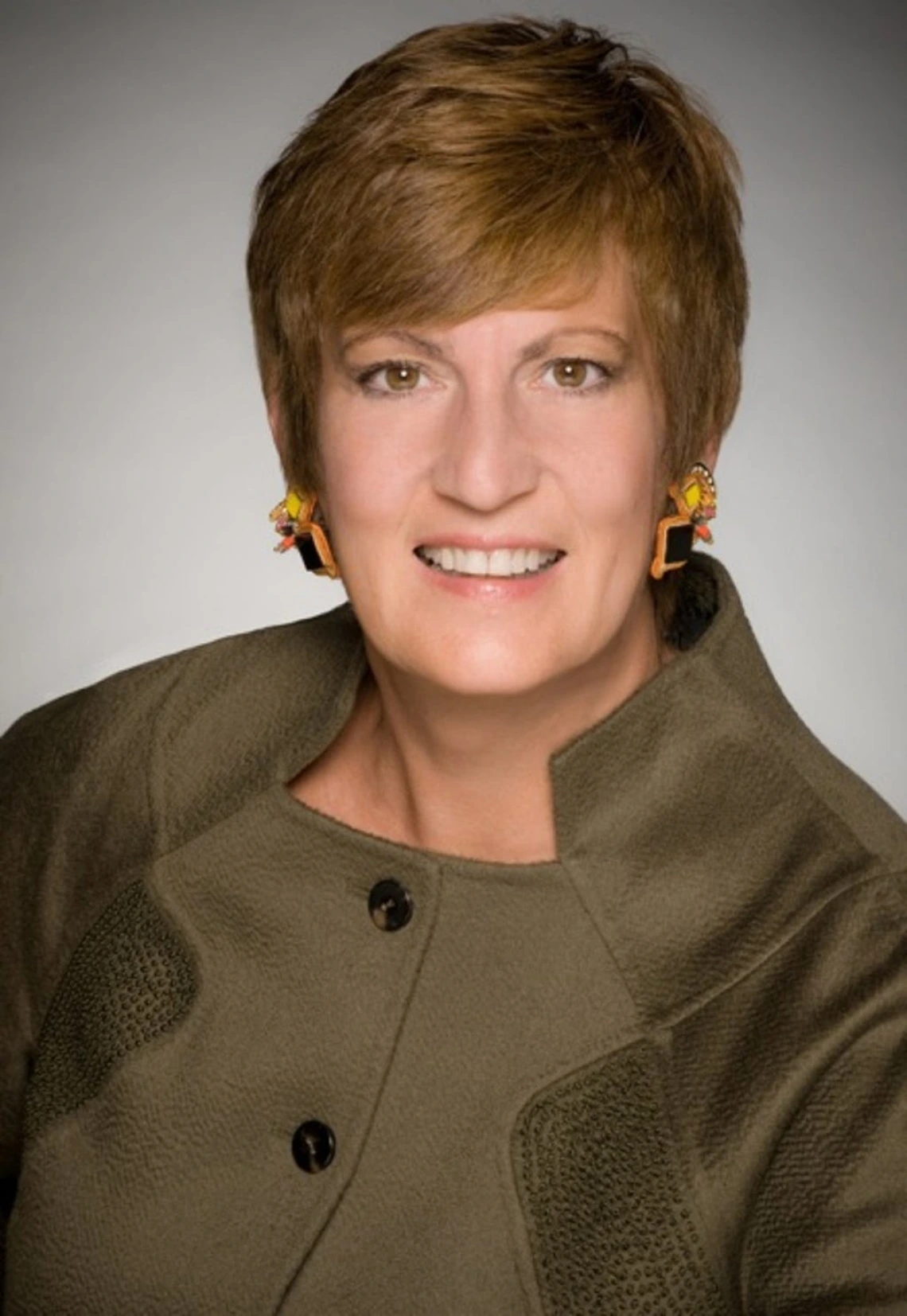 A headshot of a woman with short hair in a green shirt 