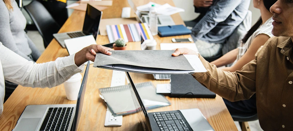 people holding file at desk