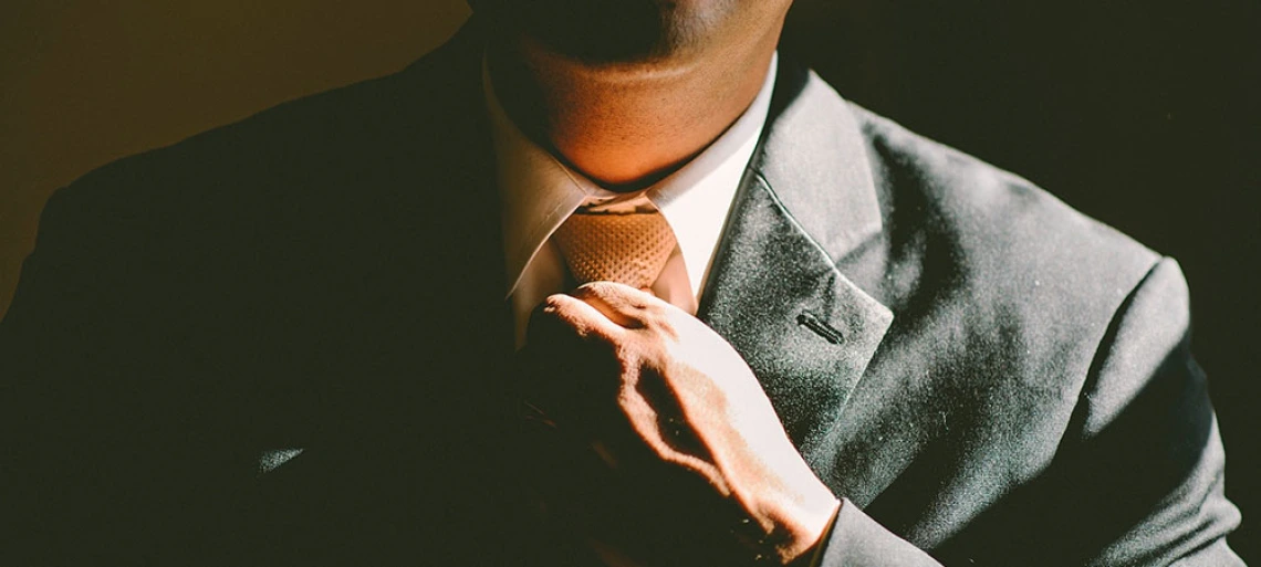 man adjusting necktie