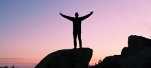 man standing on rock triumphantly